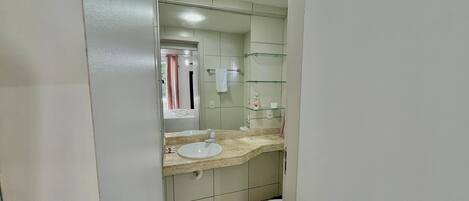 Une salle de bain équipée d’un lavabo, d’un miroir, de toilettes et d’étagères en verre.