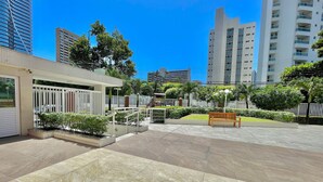 A courtyard with tiled flooring, a wooden bench, and a white fence. - Condominio Vivence (Fortaleza)