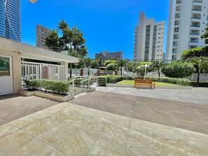 A courtyard with tiled flooring, a wooden bench, and a white fence. - Condominio Vivence (Fortaleza)
