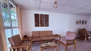 Une pièce comprenant un canapé, deux chaises en bois, une petite table et un coin repas avec des chaises et une table.