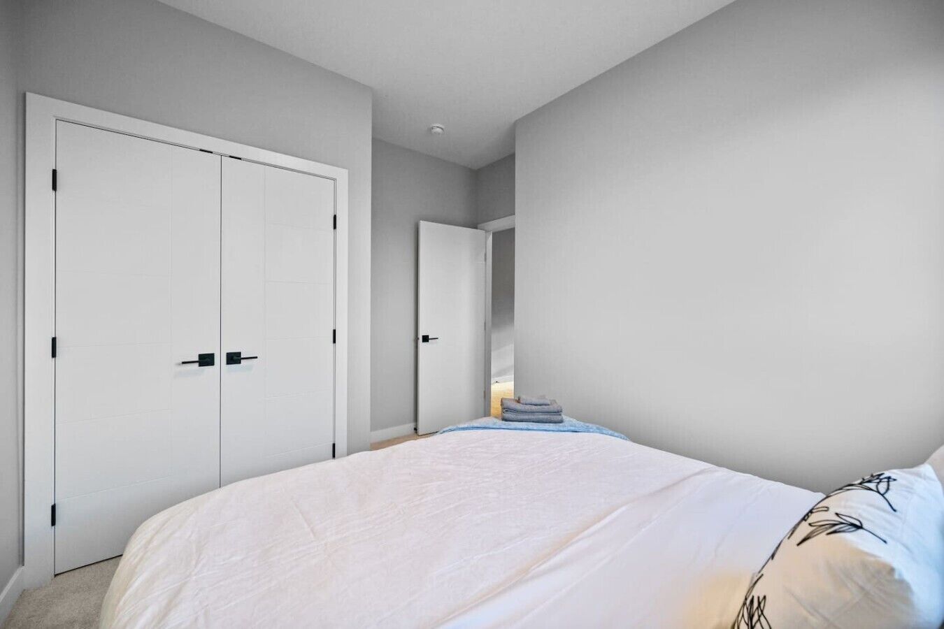 Un dormitorio con una cama grande, dos armarios y una puerta que da a otra habitación.