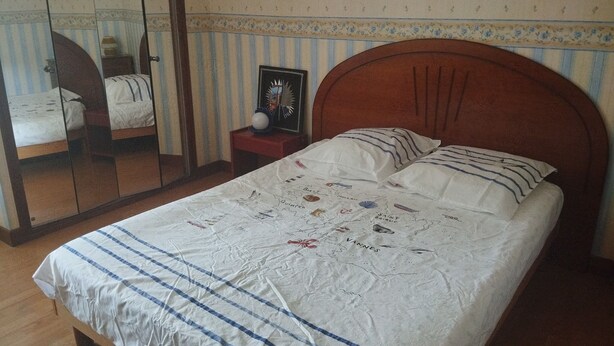 A single bed with a headboard, a bedside table with a lamp, and a mirror on the wall. - Country house 10 minutes from Saint-Jacut-de-la-mer (Corseul)