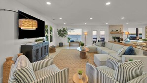 Una sala de estar moderna con televisor de pantalla plana, sofás a rayas, una mesa de centro y vista al mar.