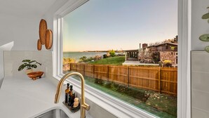 Una cocina con un ventanal grande, una valla de madera y vistas a un muelle y al agua.