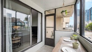 Een moderne keuken met grote ramen, een eettafel gedekt met borden en bekers, en een hangplant.