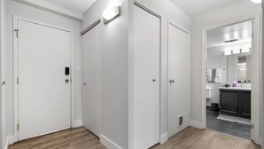 Een net appartement in moderne stijl, met witte wanden, een houten vloer en een zichtbare keuken door een open deur.
