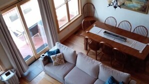 A living room with a sofa, a dining table with chairs, a chandelier, and a painting on the wall. - Mountain Retreat: Privacy & Comfort at 4,400 ft (Mars Hill)