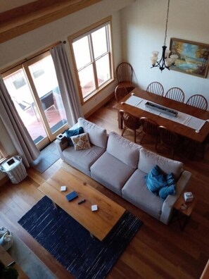 Ein Wohnzimmer mit einer Couch, einem Esstisch mit Stühlen, einer Deckenleuchte und einem Gemälde an der Wand.