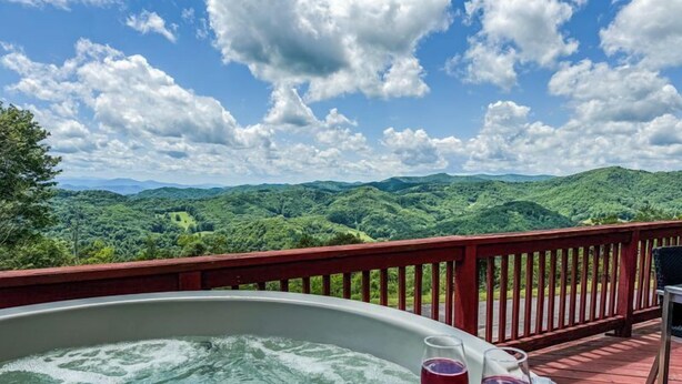 A hot tub with two glasses of red wine on a table, overlooking a mountainous landscape. - Mountain Retreat: Privacy & Comfort at 4,400 ft (Mars Hill)