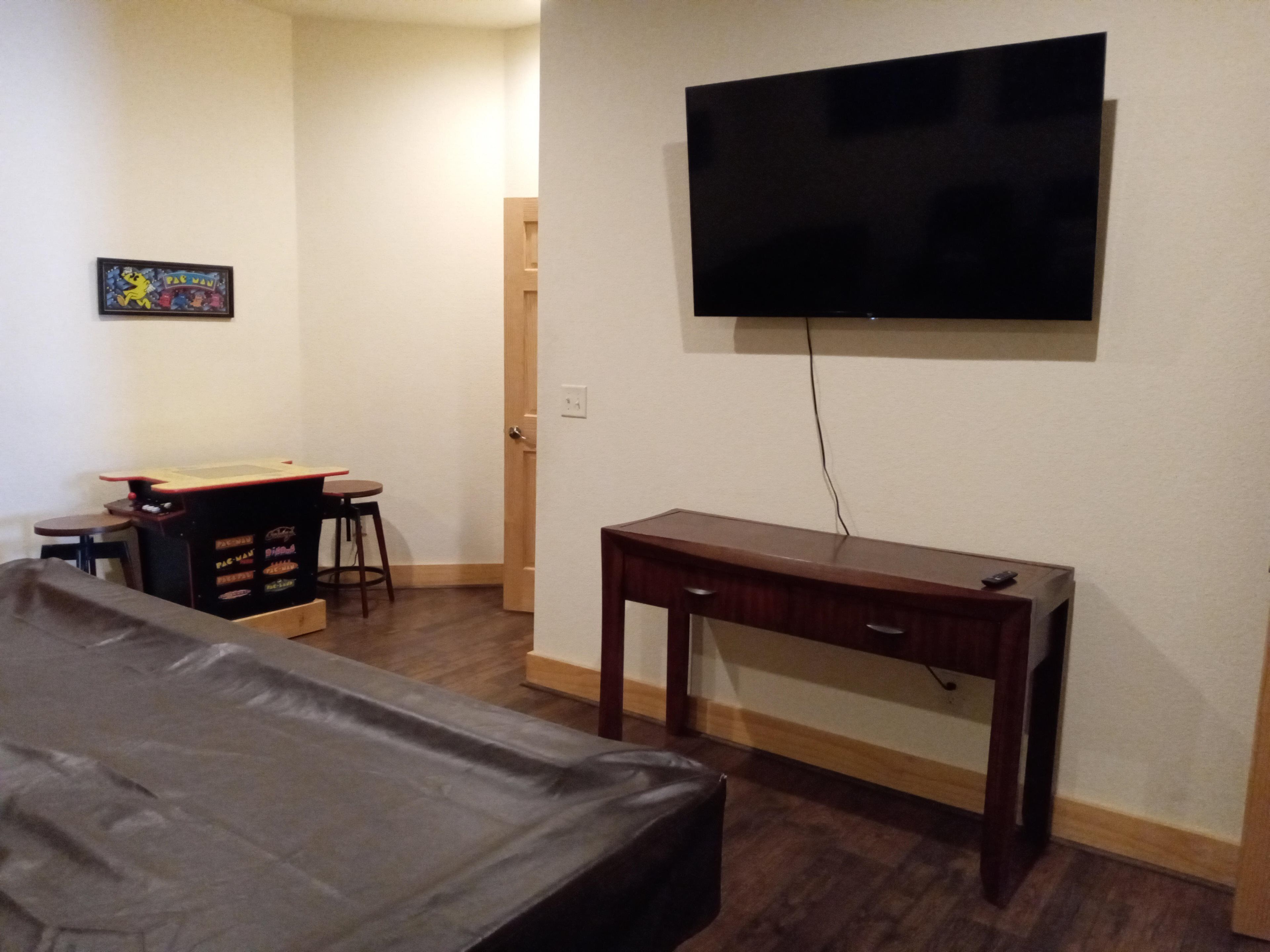 A room with a bed, a desk, a chair, a television mounted on the wall, and a door.