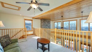 A spacious room with a wooden ceiling, a stone accent wall, a balcony with a wooden railing, and a view of the outdoors. - Mountain Retreat: Privacy & Comfort at 4,400 ft (Mars Hill)