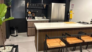 Cuina moderna amb una illa central, electrodomèstics d'acer inoxidable i una zona amb seients de fusta.