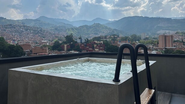 Banyera d'hidromassatge amb vista a un paisatge urbà i muntanyes.