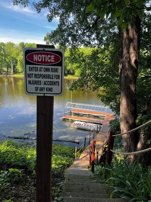 Un panneau d’information est placé près d’un quai, et une passerelle en bois mène à un endroit où l’on peut mettre les bateaux à l’eau.