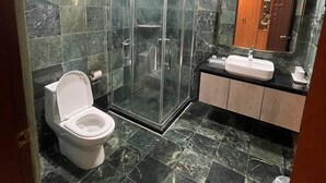 A bathroom with a glass-enclosed shower, a toilet, a sink, and a mirror.