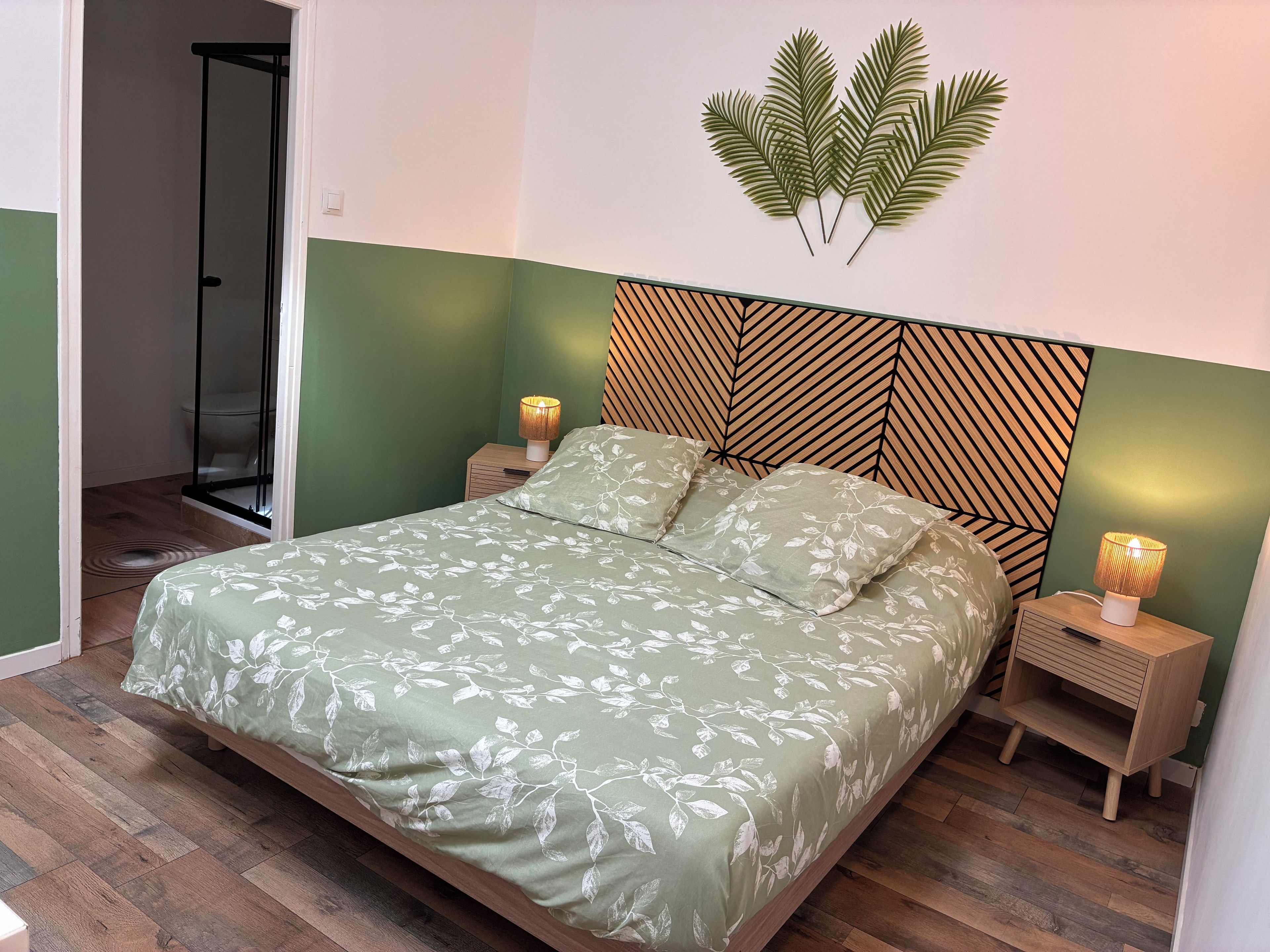 Un dormitorio con cama, mesitas de noche, una lámpara de pared y zona de ducha.