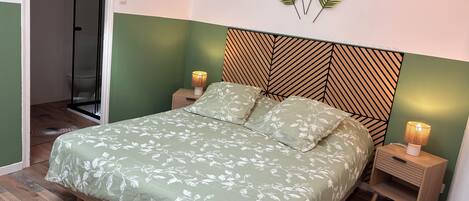 Un dormitorio con cama, mesitas de noche, una lámpara de pared y zona de ducha.