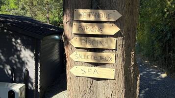 Un albero con cartelli direzionali che indicano servizi come un'area per la bocce, parcheggio, piscina, sala giochi e spa.