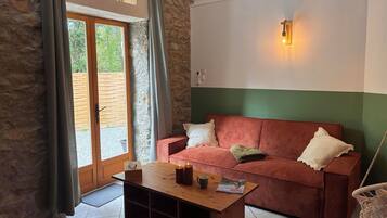 A room with a wooden coffee table, a red and white striped sofa, a green wall, and a window with curtains.