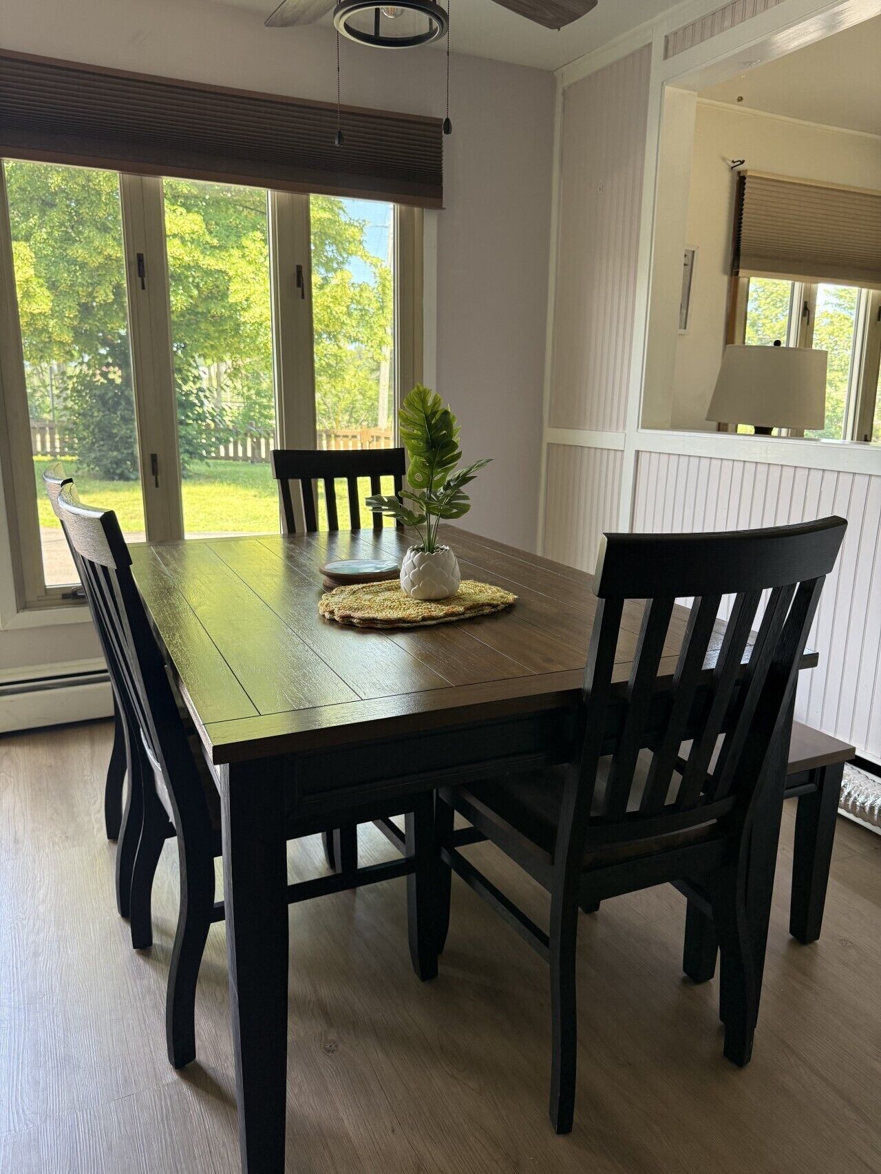 Un coin repas avec une table en bois, des chaises noires et une plante en pot.