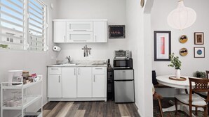 A compact kitchen with white cabinets, a stainless steel refrigerator, and a microwave.