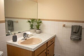 A bathroom with a sink, mirror, potted plants, and a towel rack. - Entire 2 Bedroom unit-Central location (Moncton)