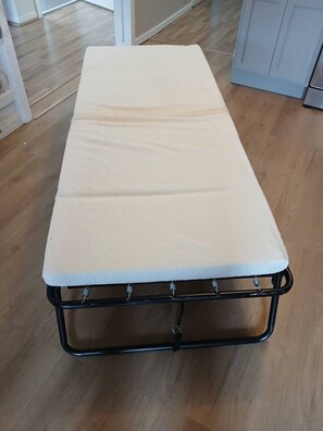 A single bed with a white mattress and black metal frame in a room with wooden flooring. - Entire 2 Bedroom unit-Central location (Moncton)