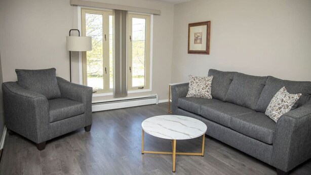 Una sala de estar moderna con un sofá gris, una mesita redonda y una lámpara de pie.