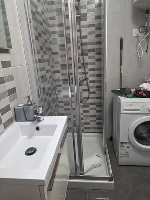 A bathroom with a glass shower enclosure, a sink, and a washing machine. - Miraverde Apartments by KHOUSE VACATION (Adeje)