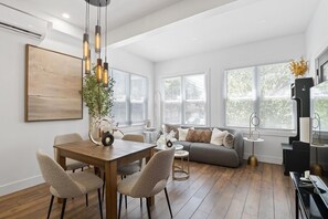 Ein modernes Wohnzimmer mit Essbereich, großen Fenstern und minimalistischem Design.