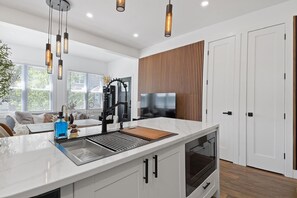 A modern kitchen with a central island, built-in oven, and a large window. - Modern Jersey City Duplex with Laundry/ Access to PATH & NYC (Jersey City)