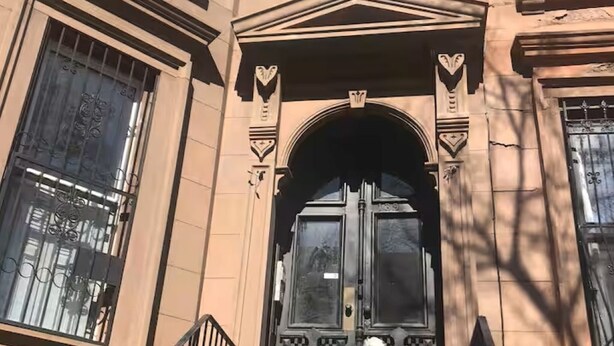 Un edificio con una entrada imponente, una escalera y un perro en primer plano.