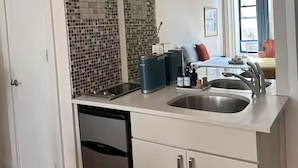 Una cocina compacta con lavavajillas, un lavabo y salpicadero de azulejos.