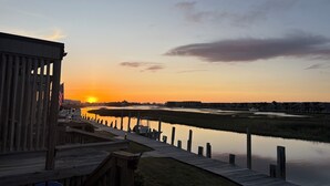Puinen laituri, joka ulottuu tyyniin veteen, ja taustalla auringonlasku.