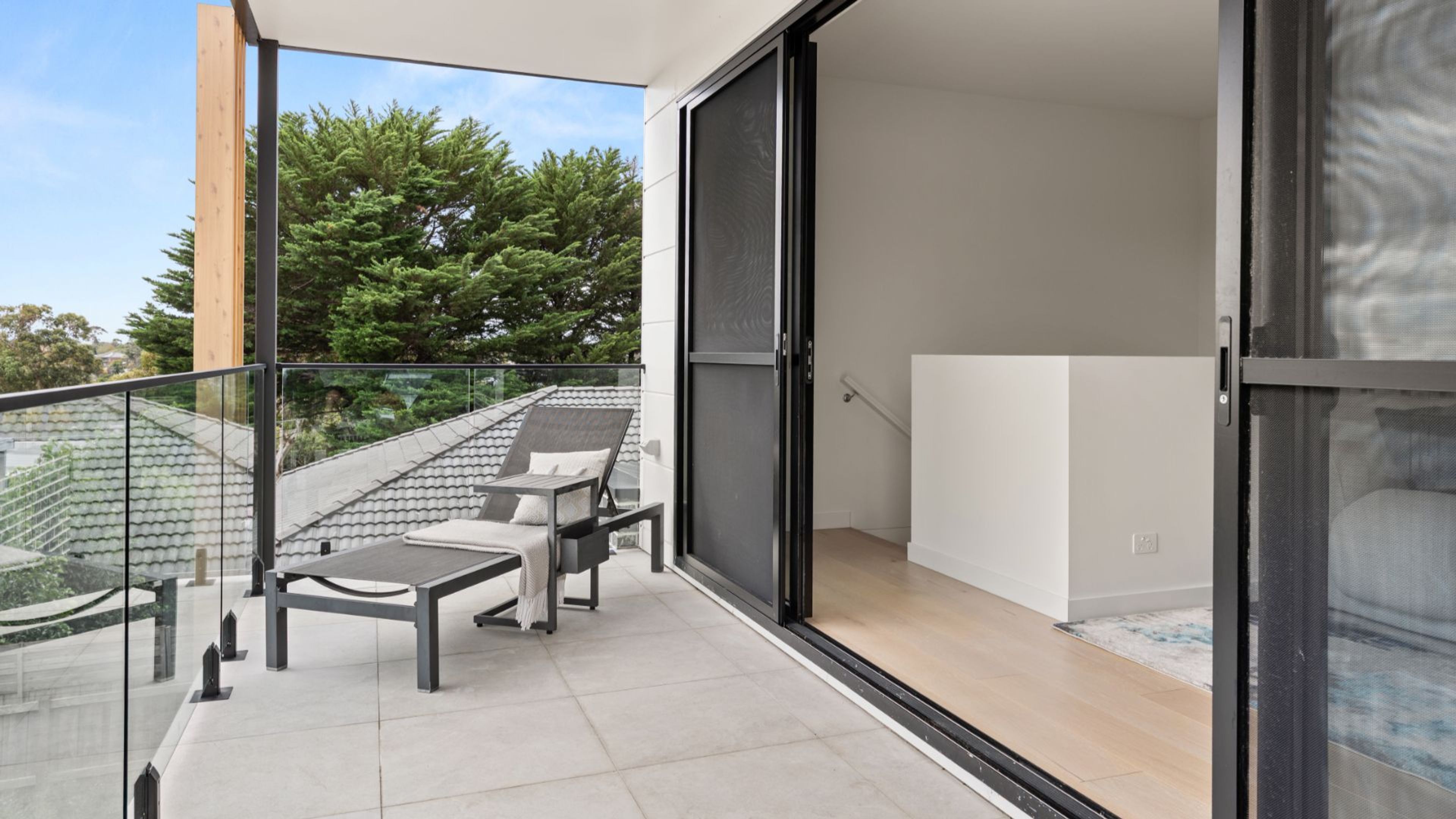 Ein Balkon mit Glasgeländer, einer Couch und einem Tisch.