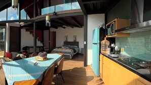 Una cuina moderna amb vitroceràmica integrada, nevera i zona de menjador amb taula i cadires.