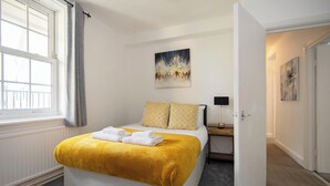 Une chambre d’hôtel avec un lit, une table de chevet, une lampe et des œuvres d’art accrochées aux murs.