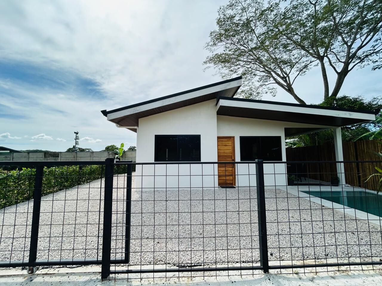 A modern house with a pool, a fenced patio, and a wooden door.