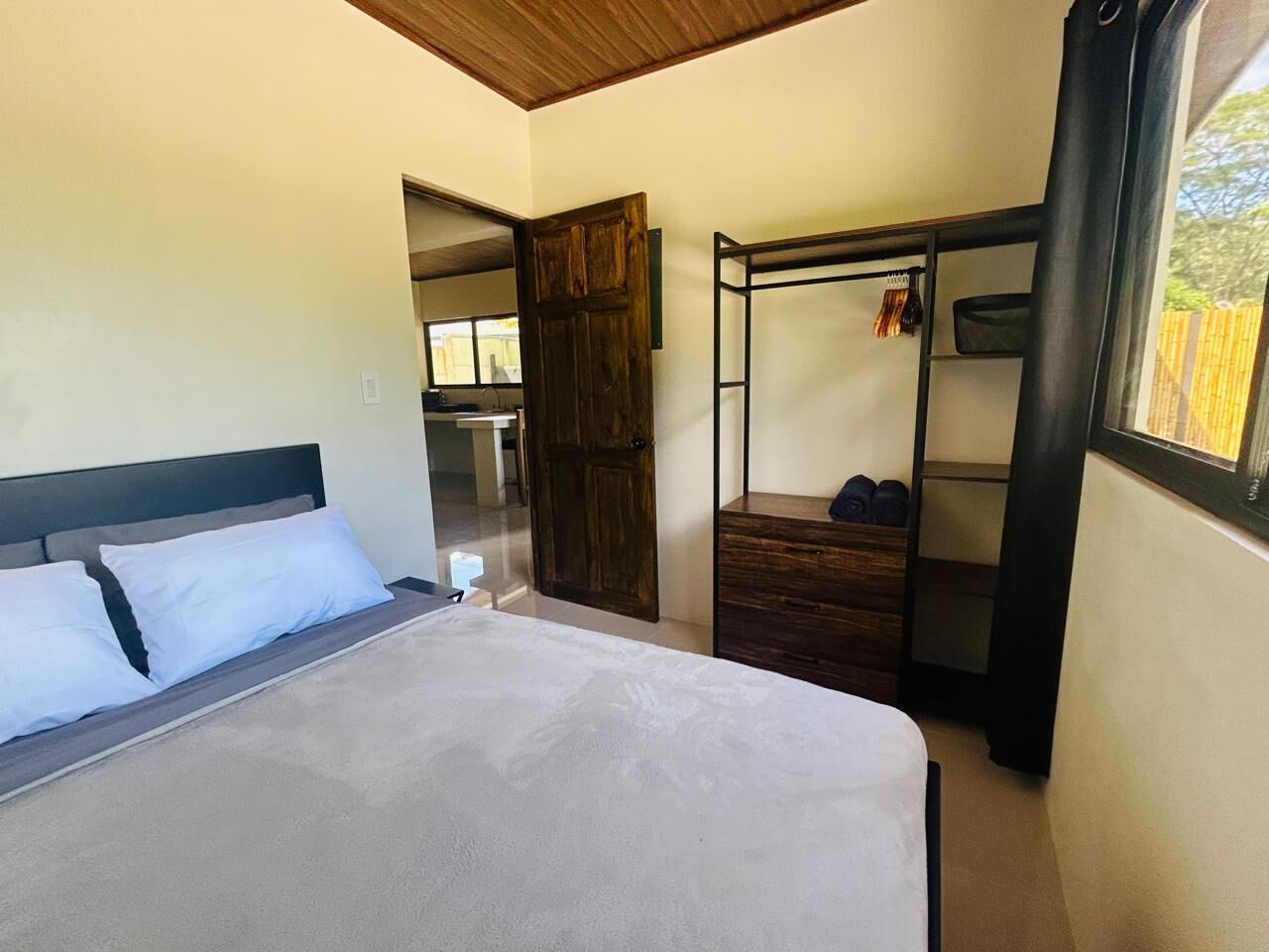 Quarto com cama, guarda-roupa e janela.