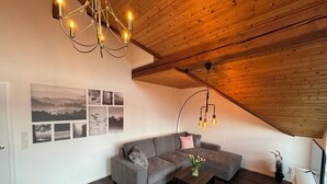 A modern living room with a wooden ceiling, a gray sectional sofa, a coffee table, and wall art. - Beautiful modern apartment - Odenwald-Panorama (Reichelsheim (Odenwald))