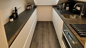 A compact kitchen with a skylight, a sink, a stove, and cabinets. - Beautiful modern apartment - Odenwald-Panorama (Reichelsheim (Odenwald))