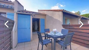 A patio with a table set for four, a blue door, and a small covered area.