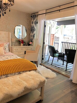 A bedroom with a bed, dresser, mirror, and a balcony with chairs. - LUX 4 Bedroom, 2 Bath Modern Farmhouse - Bear Mountain, Victoria, BC - Sleeps 8 (Victoria)
