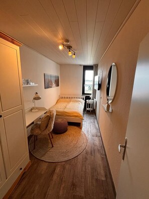 A bedroom with a bed, bedside table, lamp, chair, and a round rug. - Sea view in the Meerzeitliebe Fehmarn (Fehmarn)