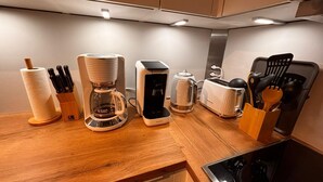 A kitchen with a coffee maker, toaster, kettle, and utensils on the counter. - Sea view in the Meerzeitliebe Fehmarn (Fehmarn)