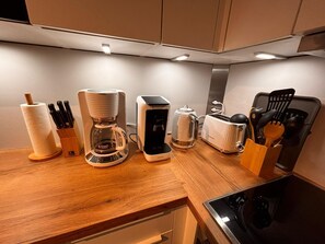 Eine Küche mit Kaffeemaschine, Toaster, Wasserkocher und Besteck auf der Arbeitsfläche.