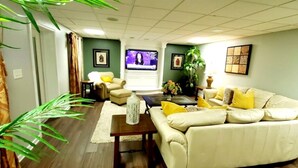 Una sala de estar con sofá, sillones, mesa de centro, televisor y planta.