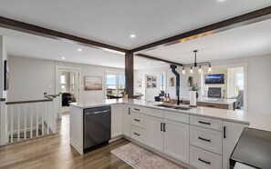 A modern kitchen with white cabinetry, a central island, and a dining area with a view. - Spacious 6 BR Water view home - Sleeps 11 - Private - Near beach (Mount Stewart)