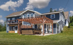 A two-story house with a covered patio area, a wooden deck, and a large garage.