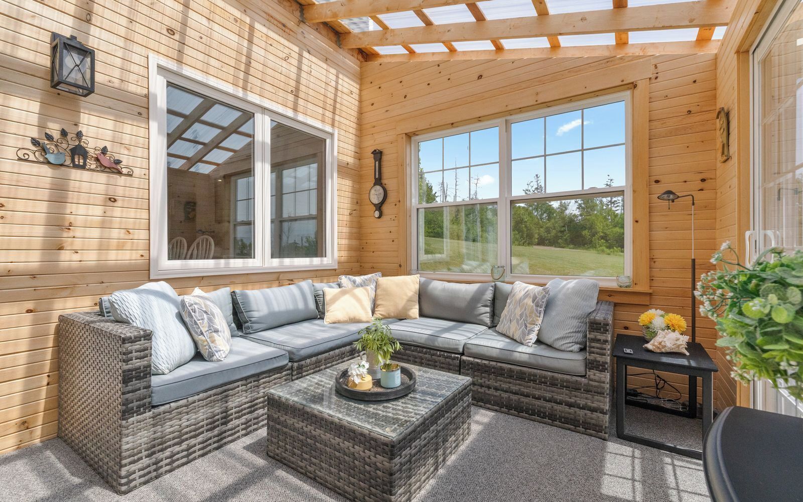 A cozy wooden interior with a sectional sofa, a small table, and a window overlooking a green landscape.
